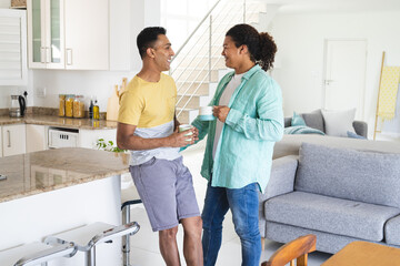 Middle Eastern man and young Biracial man, a gay couple, chatting in a bright home kitchen