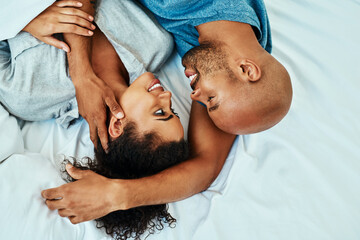 Fototapeta premium Cuddle, happy and above of couple in bed in morning for bonding, relationship and love. Marriage, home and man and woman in bedroom embrace for comfort, resting and affection for trust and care