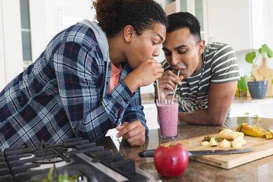 Gay biracial and Middle Eastern couple share a smoothie at home - Powered by Adobe