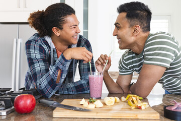 Diverse gay couple enjoys a smoothie at home