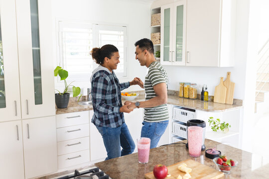 Gay biracial couple enjoys cooking together at home - Powered by Adobe