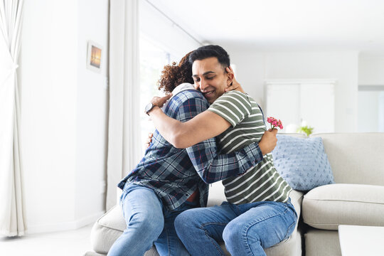 Gay biracial couple embracing joyfully at home - Powered by Adobe