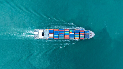 Fototapeta premium Cargo container ship carrying container and running in the ocean near international container port customs shipyard sea port concept smart logistic service. transportation logistics trading..