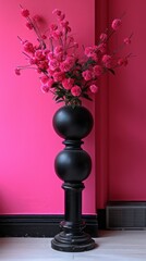 Fototapeta premium a black vase with bright pink flowers against a pink wall. The vase has a unique shape with two balls stacked on top of each other and stands on a black pedestal