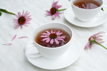 Tea with Echinacea in a white cups on marble table. Echinacea drink preparation concept. Echinacea tea. Side view, copy space. 