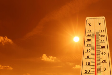Hot whether concept. A thermometer showing high temperatures under a bright and intense sun.
