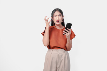 Naklejka premium Upset young Asian woman holding smartphone and appears to be angry over isolated white background.