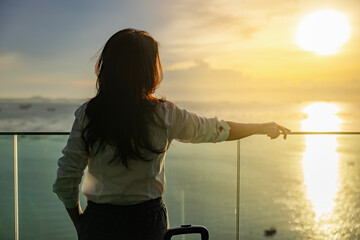 Attractive woman in beautiful beach hotel looking to beautiful view of a golden sky and the sun's rays shining on the sea, Big sun, enjoying freedom and life. Calmness, Relaxation.