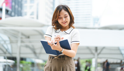 Portrait business woman writing journal note city building background