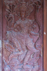 Bangkok, Thailand - June 08, 2024 : detailed wooden carving of a deity on a door temple at Bangkok, Thailand