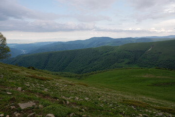 Naklejka premium Expansive view of green hills and distant mountains