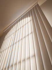 Standard closed beige vertical blinds as a detail of the bedroom interior.