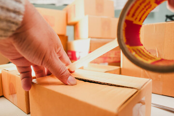 Goods delivery concept , Human hand packs merchandise into cardboard box for delivery to a customer
