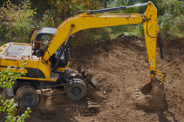 An excavator leveling a dirt site with its bucket, an excavator leveling soil, the work of an...