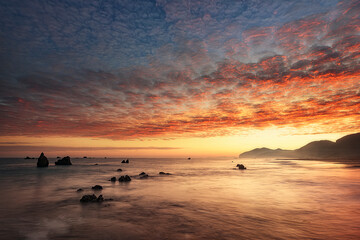 Sunrise on Noja beach with intense warm colors in the sky and reflected in the water