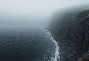 Fototapeta premium View of a dark foggy cliff with quiet sea
