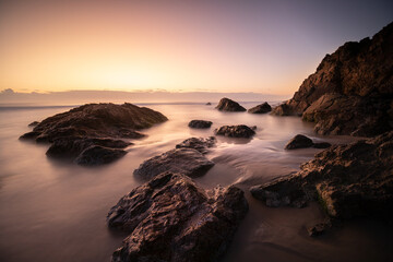 Rocky shore at Sunrise with smooth, silky water and warm light