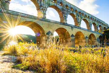 Fototapeta premium The magnificent Pont du Gard backlit by the setting sun. Photograph taken in Occitanie, France