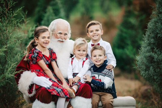 Santa with four kids in festive attire at a Christmas tree farm