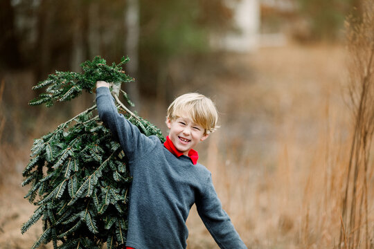 Boy carrying a Christmas tree outdoors
