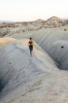 Female runner training among desert gullies.