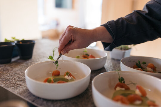 Chef garnishing gourmet dishes in a kitchen with fresh ingredients