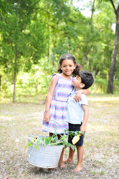 Happy siblings holding a basket of harvested vegetables, smiling outdo