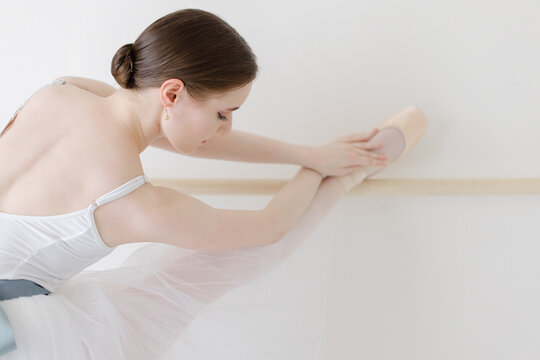 ballerina stretches on ballet barre with bun in hair