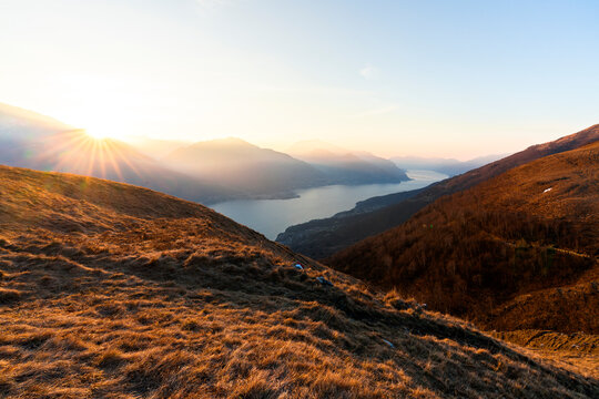 Foggy sunrise over mountains above Lecco branch of Lake Como in autumn
