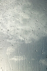 Rain droplets cascade down glass window © Serhii