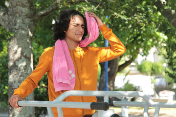 Naklejka premium young man in training equipment in the park fatigued making a break