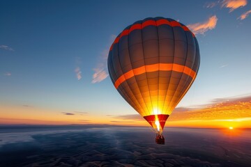 Fototapeta premium A majestic hot air balloon floating peacefully against a clear blue sky at sunrise, with the golden hues of the rising sun casting a warm glow over the horizon. The intricate details of the balloon's