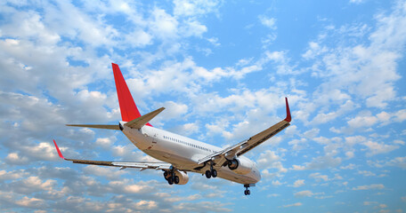 Passenger airplane landing to airport with bright cloudy sky - White passenger airplane flying in the sky amazing clouds in the background - Travel by air transport
