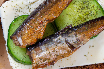 Sandwich black bread with sprats, cheese, cucumber and herbs. Snack for vodka