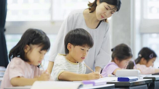 勉強をする小学生に指導する教師