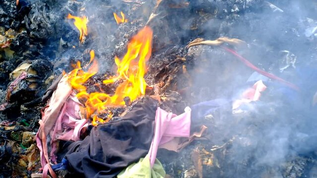 Footage of fire burning cloth and plastic waste. Burning waste on the roadside. Environmental Pollution. Air Pollution. Industrial waste destruction. 4K Resolutions 30 Fps Video