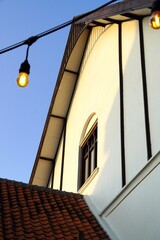 Classic house with a triangular roof, brown window in the center, and off-white yellowish walls.