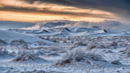 A vast, snowy landscape with a mountain range in the background, captured during a sunset with a dramatic sky.