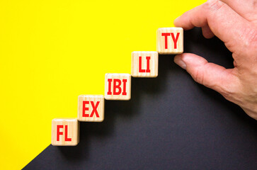 Flexibility symbol. Concept word Flexibility on beautiful wooden cubes. Beautiful yellow and black background. Businessman hand. Business flexibility concept. Copy space.