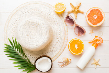 Top view of various seashells placed near colorful fruit and stylish summer accessories on table...
