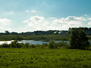 Landscape of meadow and pond in background.