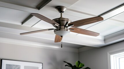 A white ceiling fan with five blades and three lights hangs from a white ceiling. The fan has gold accents around the motor and light fixtures. The lights are covered in white shades