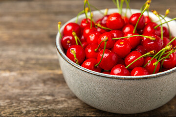Cherries. Fresh ripe cherries with leaves on a textured wooden background. Fresh sweet organic cherry pile. Berries and fruits. Vegan. Healthy eating. Place for text. Copy space