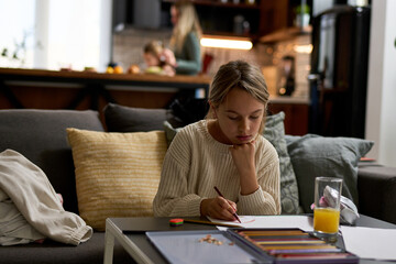 Portrait of a girl immersed in creativity, sketching away at a table in the living room, bringing art to life.