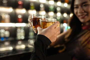 Close up shot of two friends toasting with drinks in the bar. Nightlife, celebrations and friendship concept