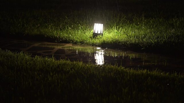 4K: Rainy night scene in Georgia, with raindrops falling on the garden ground light.