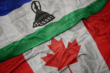 waving colorful flag of lesotho and national flag of canada on the dollar money background. finance...