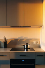 Cozy kitchen background with morning sun light, glass ceramic hob with saucepan