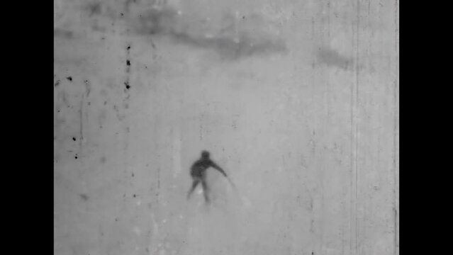 Archival film, People skiing on white snowy mountain slope backdrop in winter. Man slid down from snowy mountain slope. Extreme retro active recreation. Vintage black white film. Alpine 1960s archive