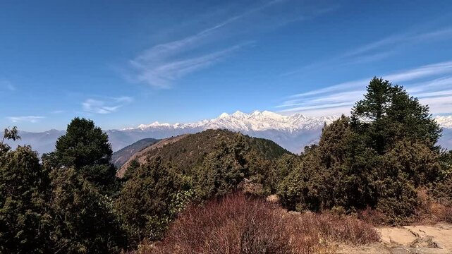 High altitude panorama with pine forests,  snowy Ganesh Himaly mountain range with a hut in the foreground. Blue sky cloud valley. Lauribina, Himalayas of Nepal. Langtang Trek and Gosaikunda Trek